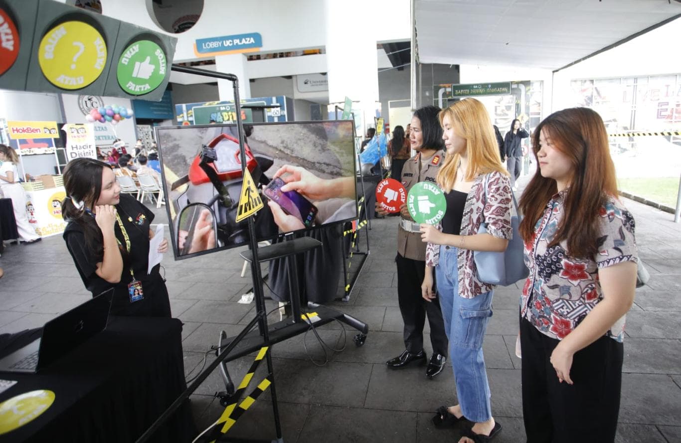 EDUKASI: Mahasiswa UC Michelle Wokas (kiri) dan Kanit Kamsel Satlantas Polrestabes Surabaya AKP Santa
Yulia (tiga dari kanan) menjelaskan materi safety riding lewat video pada program SADIVE 2025 Rabu (19/11)