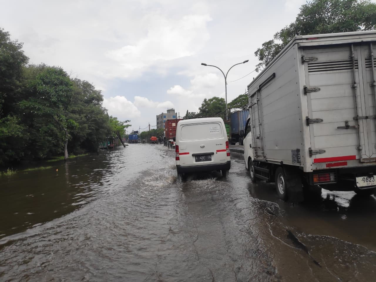 JALAN MENYEMPIT: Genangan Jalan Tambak Langon Rabu (12/11) siang ditangani petugas dengan pembersihan saluran.