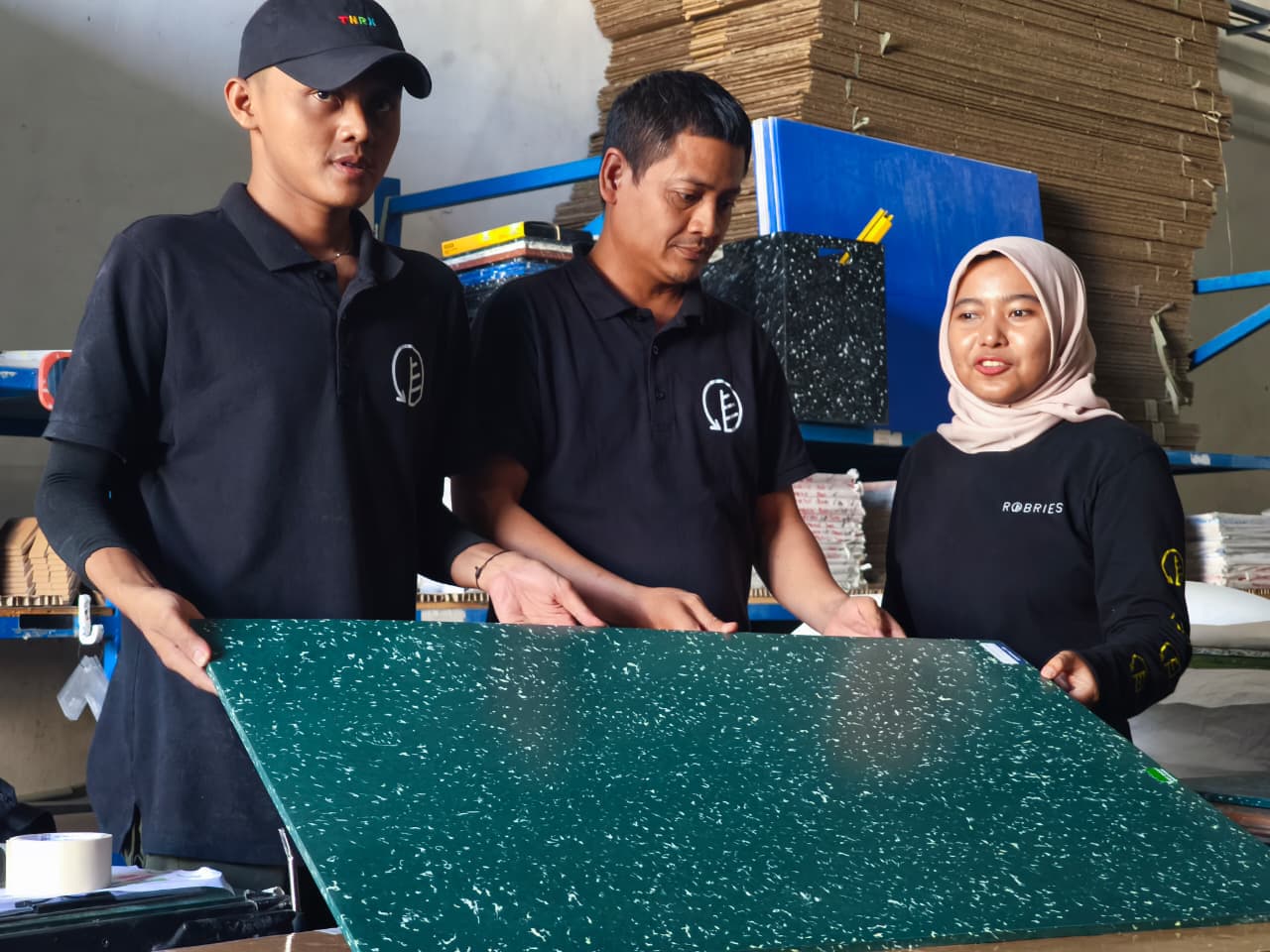 PANTAU LANGSUNG: Ni’am (kanan) mengecek papan plastik, hasil peleburan tutup botol. Dari bentuk tersebut, bisa langsung dicetak menjadi gantungan kunci maupun tatakan gelas.